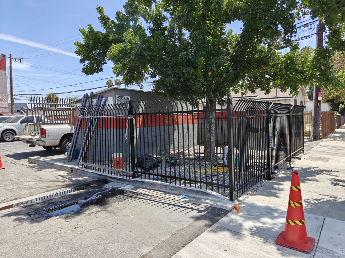 Completed black steel commercial security fence with anti-climb spear tops on a Bell Gardens, CA corner lot by Apexguard Fence