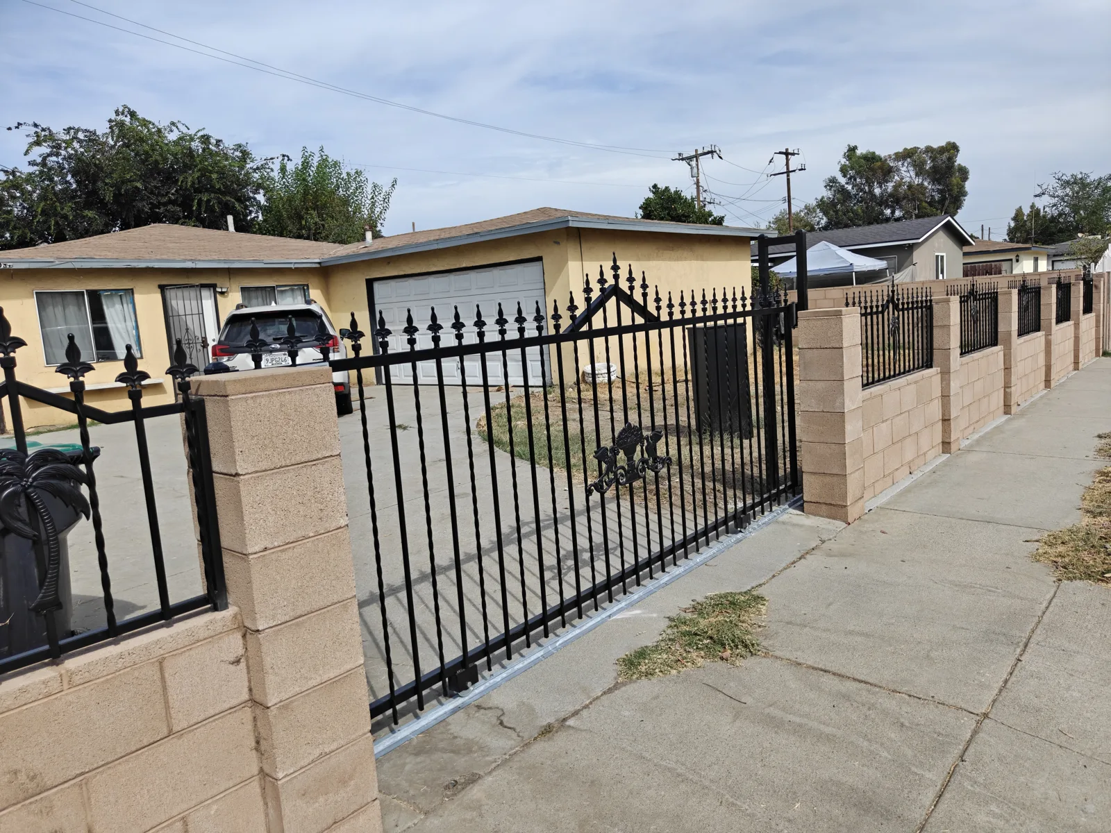 Ornamental iron fence on block wall running along the sidewalk in Baldwin Park, CA by Apexguard Fence