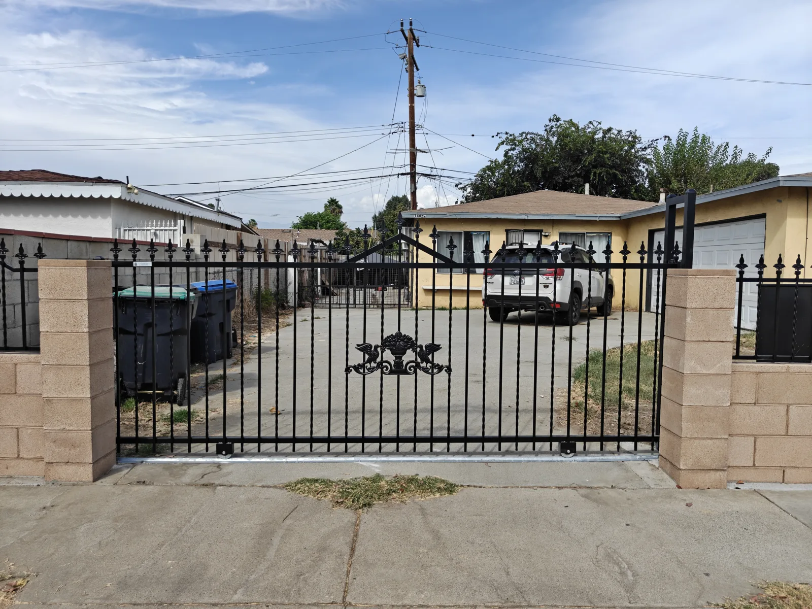 Sliding ornamental iron driveway gate with decorative medallion — a real Apexguard Fence project in Baldwin Park, CA