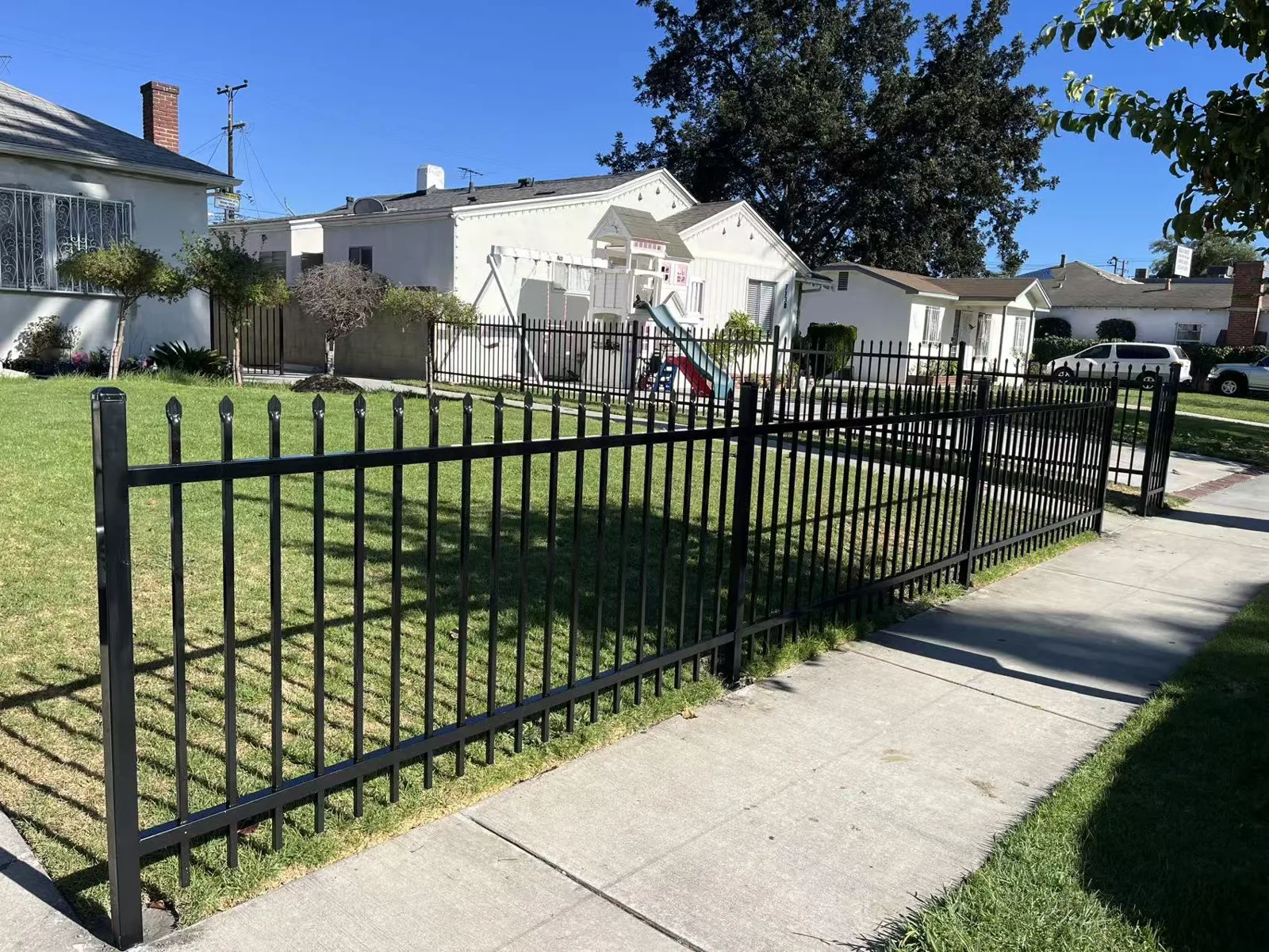 4 ft black spike-top wrought iron fence wrapping a corner front lawn — a real Apexguard Fence project in Huntington Park, CA