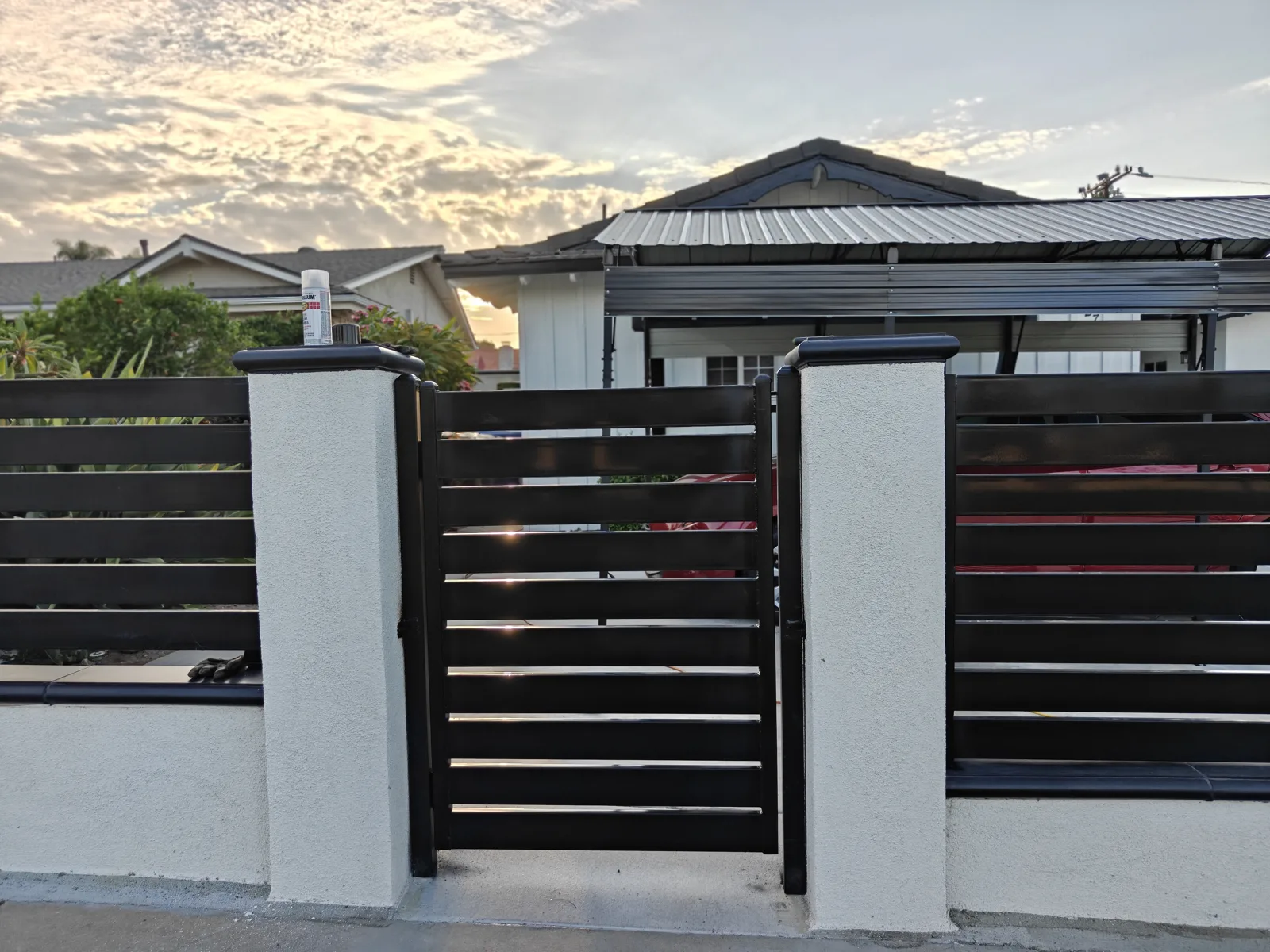 Matching black horizontal slat walk gate between white stucco pilasters in La Puente, CA by Apexguard Fence