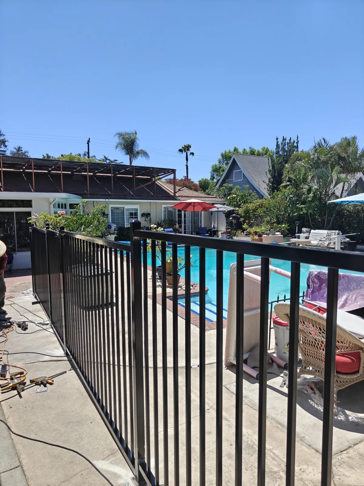 Black iron pool fence run with turquoise pool water behind — a real Apexguard Fence project in Ontario, CA