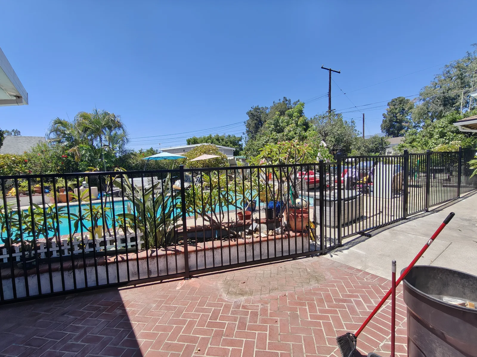 Black flat-top iron pool safety fence along a brick patio — a real Apexguard Fence project in Ontario, CA