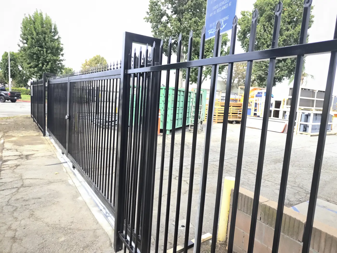 23 ft single sliding gate parked along its poured concrete track run beside the fence line in Whittier, CA