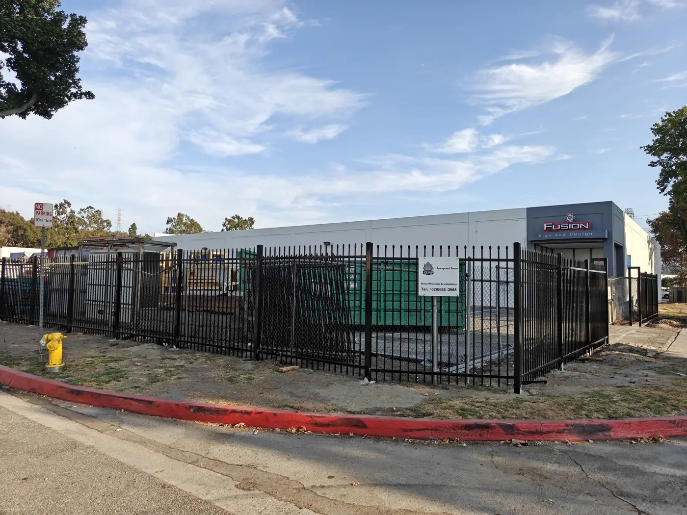 7 ft commercial spike-top steel security fence with 24 ft bi-parting and 23 ft single sliding gates at a Whittier, CA sign manufacturing facility by Apexguard Fence