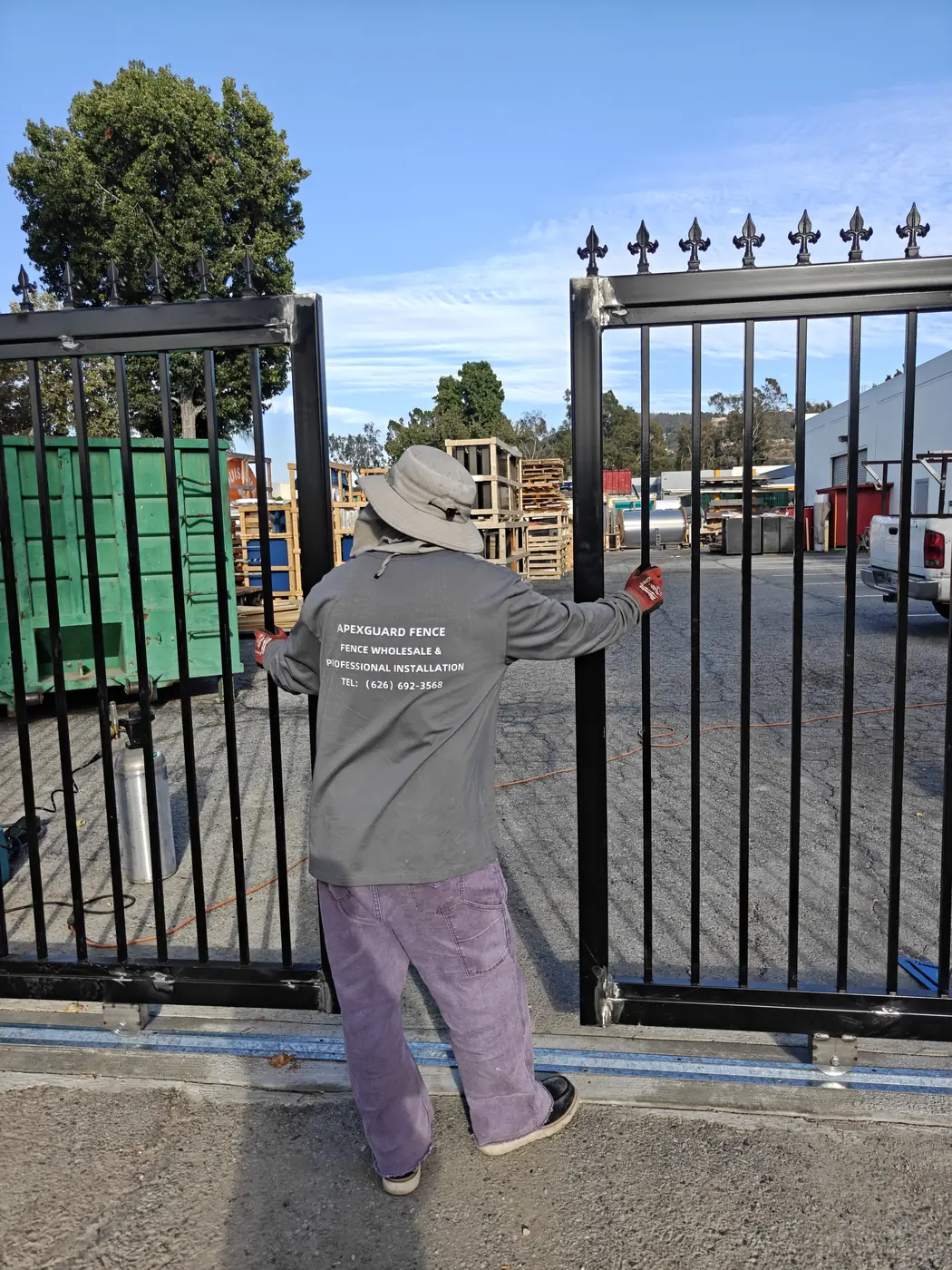 Apexguard Fence installer setting and aligning a steel sliding gate leaf onto its ground track in Whittier, CA