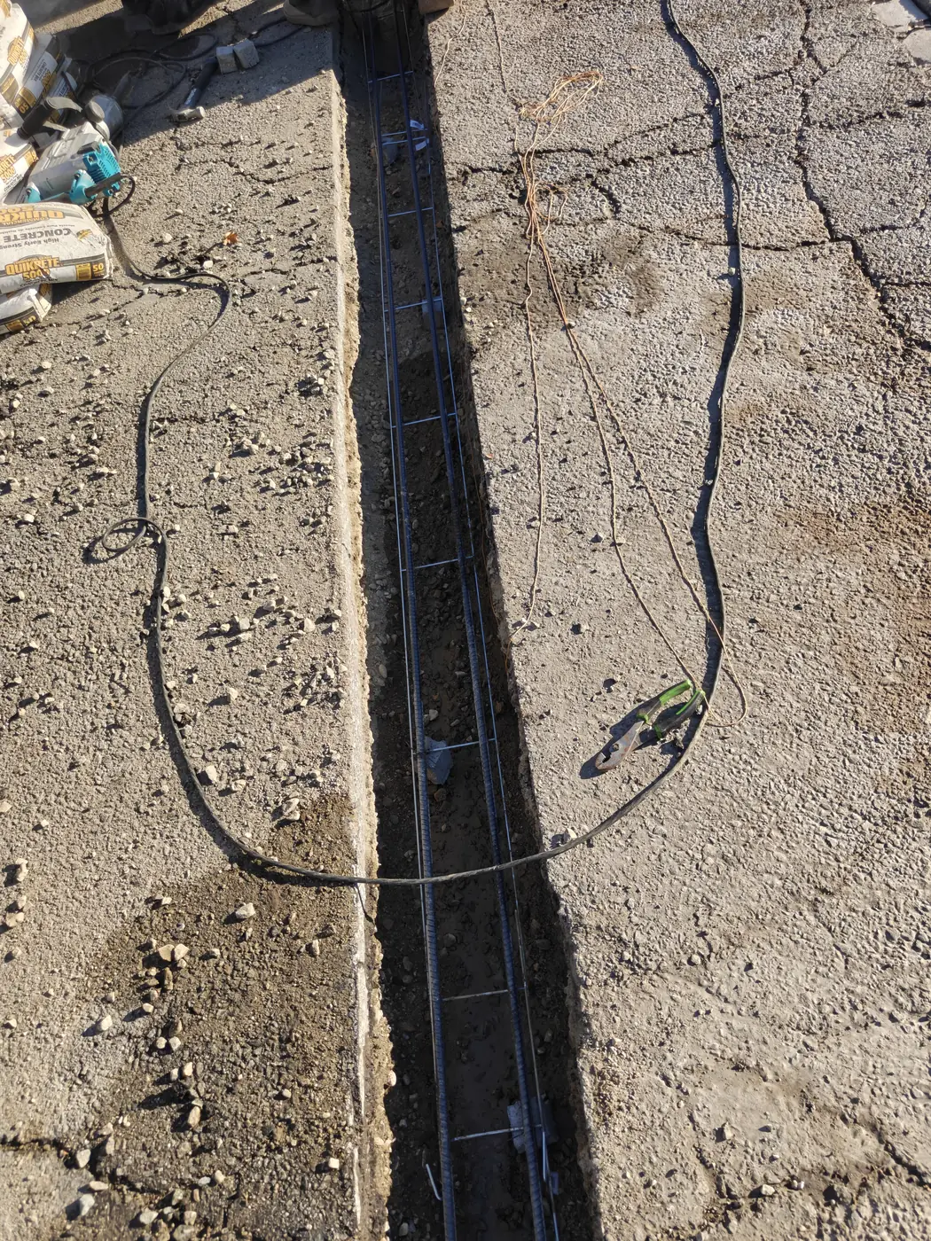 Steel sliding gate track rail set in an open trench with rebar before the concrete pour in Whittier, CA