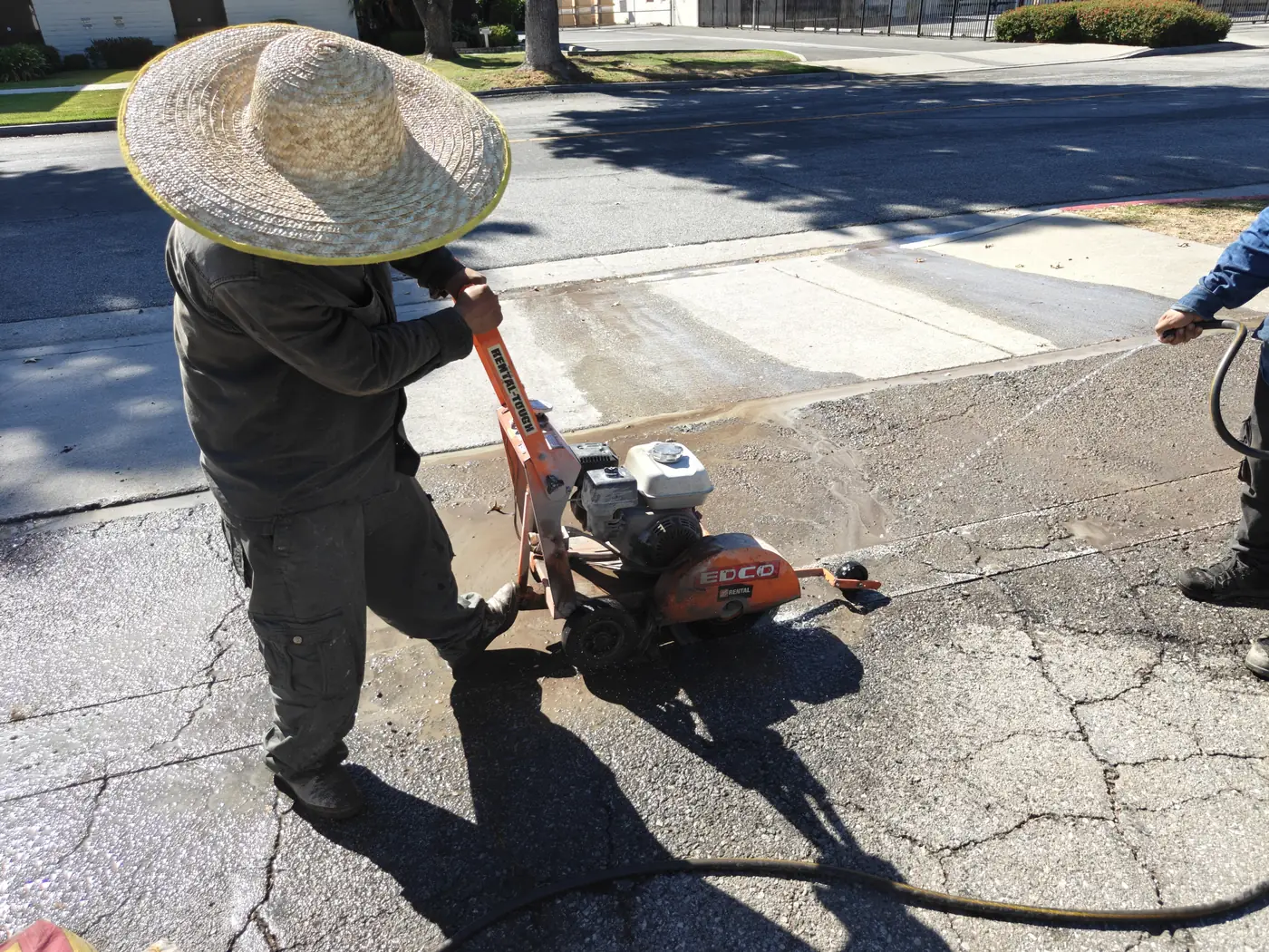 Crew saw-cutting asphalt with a walk-behind concrete saw to open the sliding gate track line at a Whittier, CA commercial yard